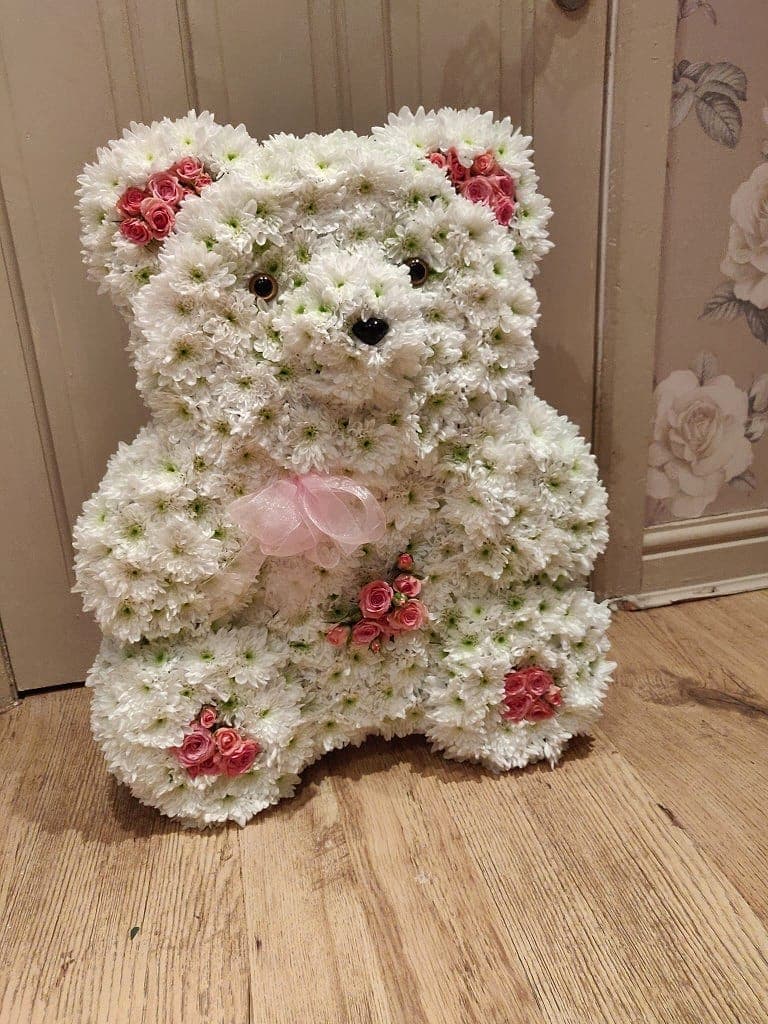 Sitting teddy-bear tribute of white chrysanthemums with pink rosebuds and a sheer pink bow
