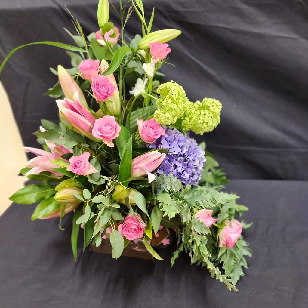 Bespoke arrangement of roses, lilies and hydrangea allowed to fall and soften rather than sit neatly in place