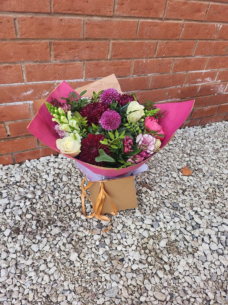 Gift bouquet of deep burgundy chrysanthemums and cream roses, gathered in kraft