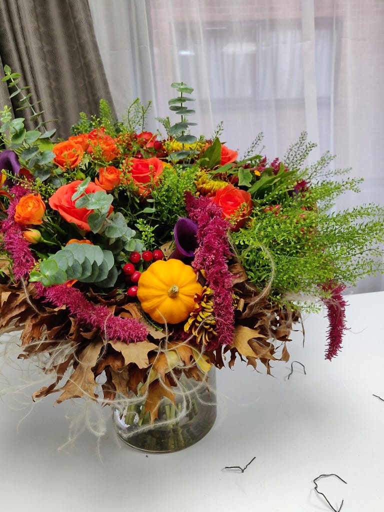 Seasonal autumn arrangement of orange roses, calla lilies, amaranthus and pumpkin