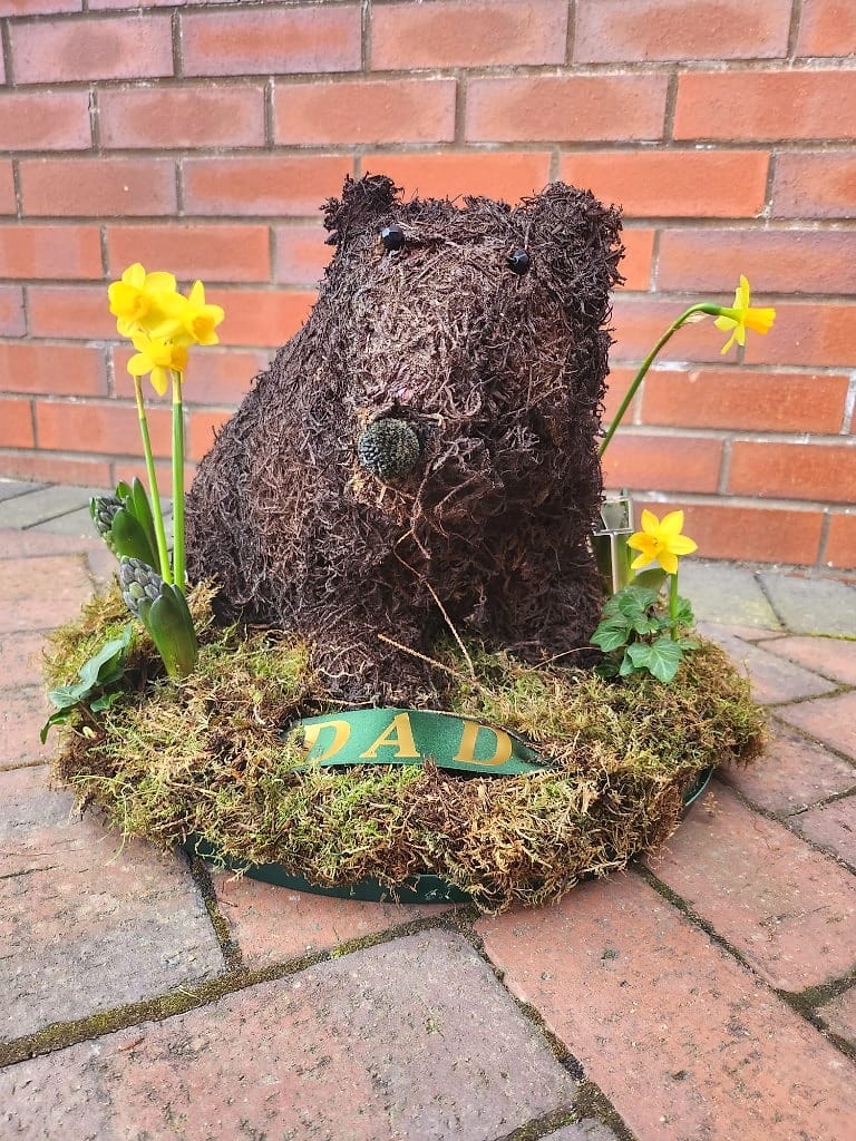Shaped tribute as a moss bear, finished with daffodils and ribbon — made for Dad