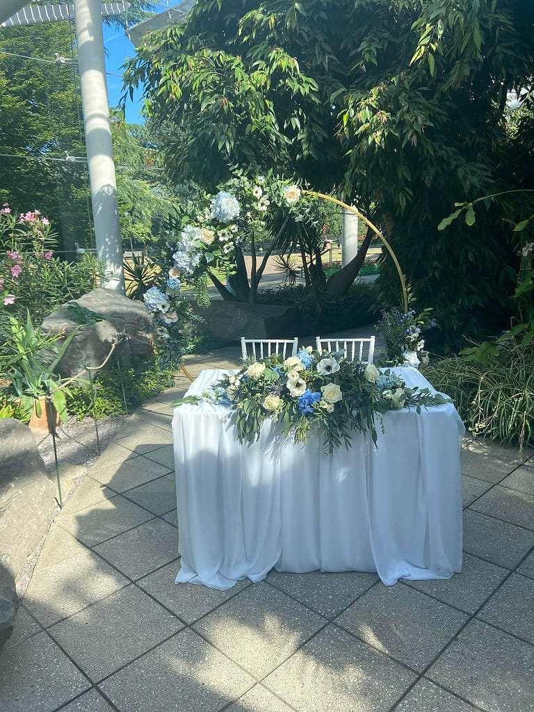Ceremony hoop, flower-lined table and garden — one floral story carried through the setting